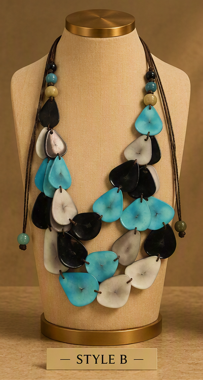 A multi-strand statement necklace displayed on a beige fabric mannequin bust. The necklace features alternating layers of glossy black and bright turquoise blue teardrop shell-like beads, accented with small turquoise and beige beads on dark cords.