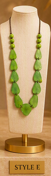 A green beaded necklace displayed on a beige fabric mannequin bust with a gold stand. The necklace features multiple layers of green beads, including teardrop-shaped beads and smaller round beads.