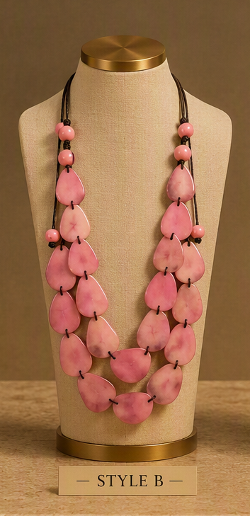 A pink stone bead necklace displayed on a beige fabric jewelry bust with a gold-toned top and base. The necklace has multiple strands of irregular pink stone beads on black cords, with small pink spacer beads.