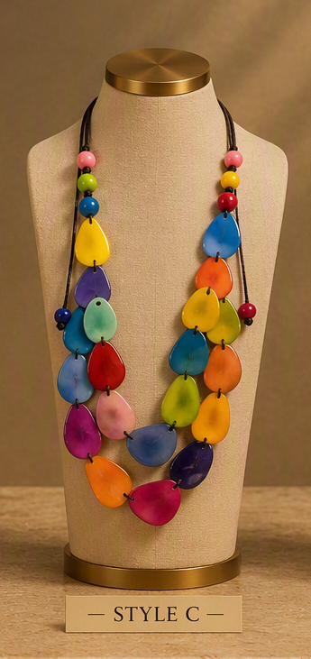 A multicolor beaded necklace displayed on a beige fabric mannequin bust. The necklace features multiple strands of glossy, teardrop-shaped beads in a rainbow of colors including yellow, blue, green, orange, pink, purple, and red, accented with small round beads on black cords.