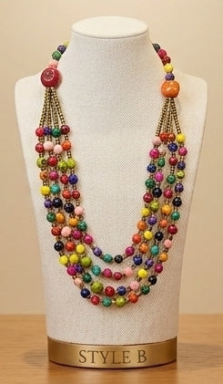 A multi-strand beaded necklace displayed on a cream fabric mannequin bust. The necklace features multiple strands of colorful round beads in red, orange, yellow, green, blue, pink, and purple, with gold-tone chain links.