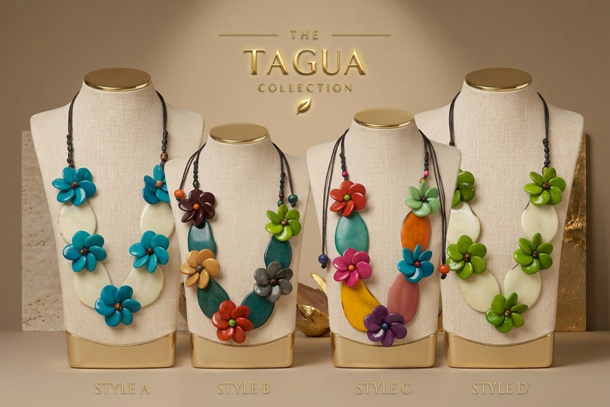 Four Tagua collection necklace styles displayed on beige fabric mannequin busts against a warm beige background. The necklaces feature colorful carved tagua flower and oval elements in blue, green, orange, pink, purple, and brown, with gold-toned caps and cords.