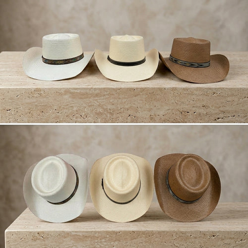Three cowboy-style straw hats in white, cream, and brown are displayed on a stone surface against a textured beige wall, shown in two rows. Ecuadorian Toquilla Straw Panama Hats.