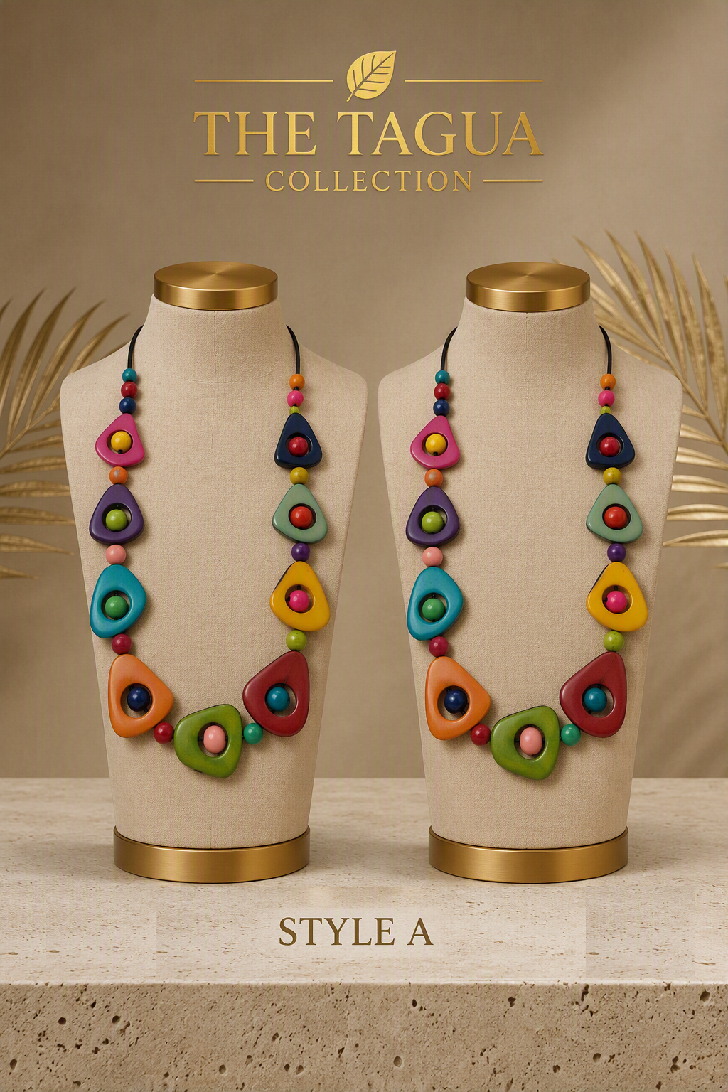 Two beige jewelry display busts wearing matching colorful statement necklaces from The Tagua Collection, shown against a warm beige background with decorative palm leaves and the text 'THE TAGUA COLLECTION' and 'STYLE A'.
The Tagua Classic Beaded Necklace in Style A, Ecuadorian tagua necklace.