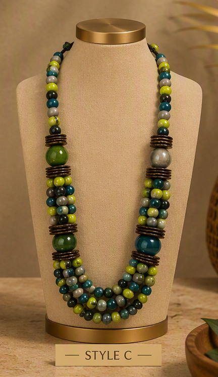 A multi-strand beaded necklace displayed on a beige fabric jewelry bust. The necklace features strands of dark teal, forest green, lime green, and gray beads, separated by dark brown textured spacer rings.