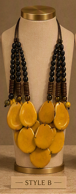 A statement bib necklace displayed on a beige fabric mannequin bust. The necklace features three strands of glossy black beads, brown spacer beads, and a large central cluster of irregular, teardrop-shaped yellow stone pendants.