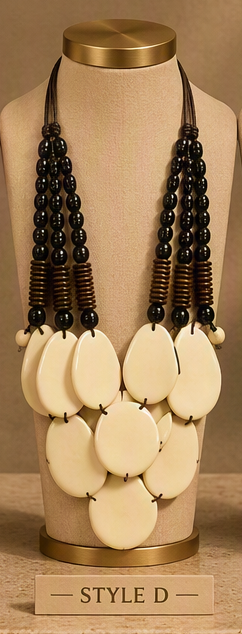 A statement necklace displayed on a beige jewelry bust. The necklace features multiple strands of dark beads, brown textured spacer beads, and a large cluster of round cream-colored disc pendants at the bottom.